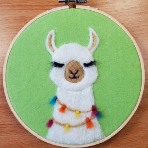 a white alpaca needle felted on bright green fabric