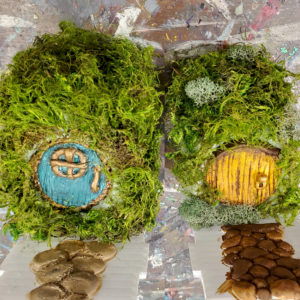 two miniature hobbit houses with round doors, one green and one yellow